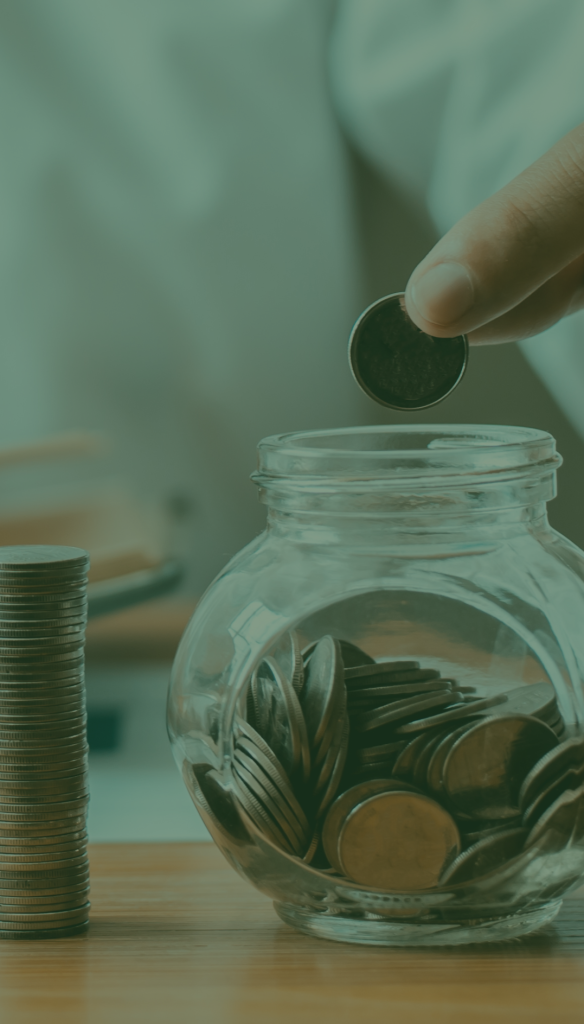 Man putting a coin into a coin jar next to a stack of coins.